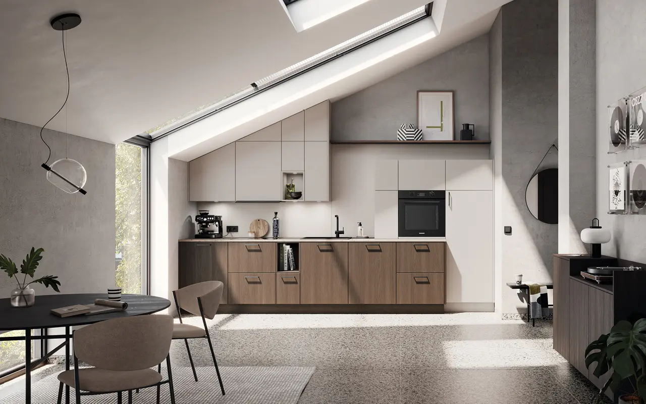 Zeitlose Küche in heller Holzoptik und Beige unter einer Dachschräge. Moderne Planung mit integrierten Geräten, minimalistischer Einrichtung und stilvollem Tageslichtambiente.